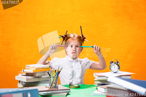 Image of The Redhead teen girl with lot of books at home. Studio shot