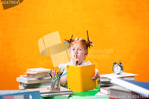 Image of The Redhead teen girl with lot of books at home. Studio shot