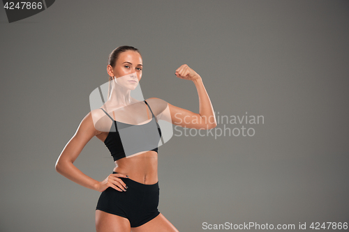Image of Muscular young woman athlete on gray