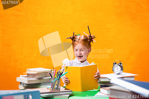 Image of The Redhead teen girl with lot of books at home. Studio shot