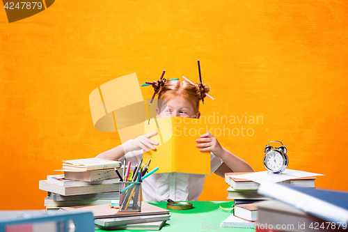 Image of The Redhead teen girl with lot of books at home. Studio shot