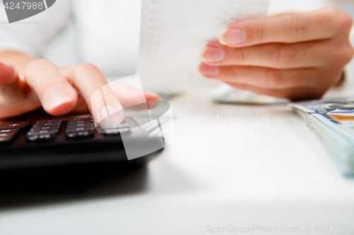 Image of savings, finances, economy and home concept - close up of hands with calculator counting money and making notes at home