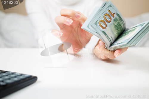 Image of business, finance, saving, banking and people concept - close up of woman hands counting us dollar money