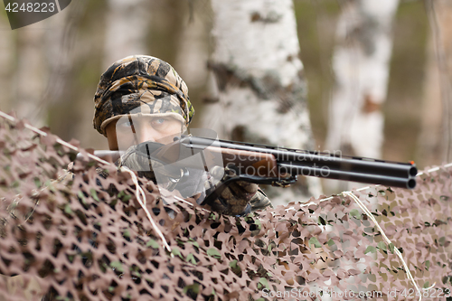 Image of hunter aiming from behind camouflage netting