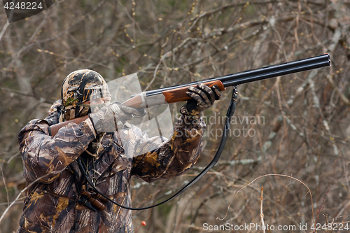 Image of hunter in camouflage takes aim from a gun