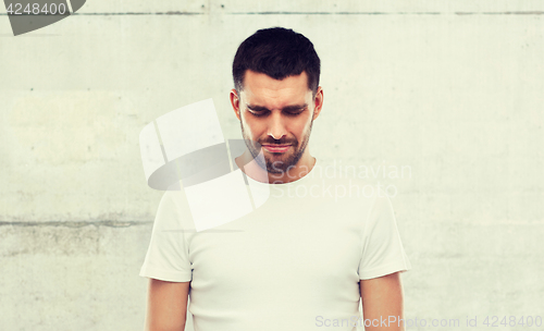 Image of unhappy young man over gray wall background
