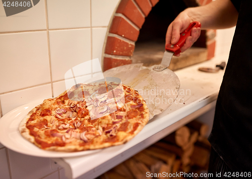 Image of chef placing pizza from peel to plate at pizzeria