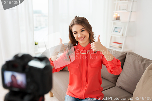 Image of woman with camera recording video at home