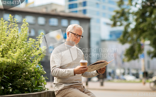 Image of senior man reading newspaper and drinking coffee