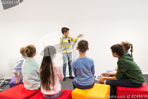 Image of happy student boy showing something at white wall