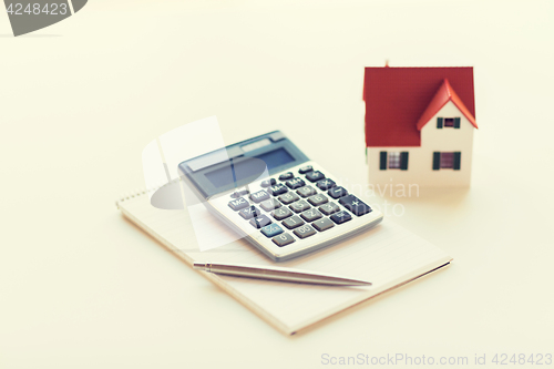 Image of close up of home model, calculator and notebook