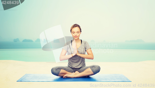 Image of woman making yoga meditation in lotus pose on mat