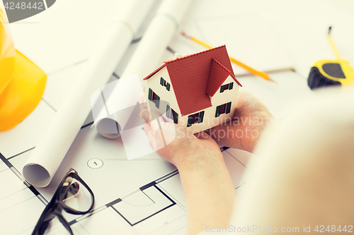 Image of close up of hands with house model above blueprint