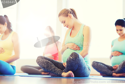 Image of happy pregnant women exercising yoga in gym