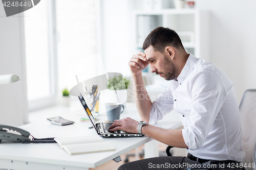 Image of stressed businessman with laptop at office