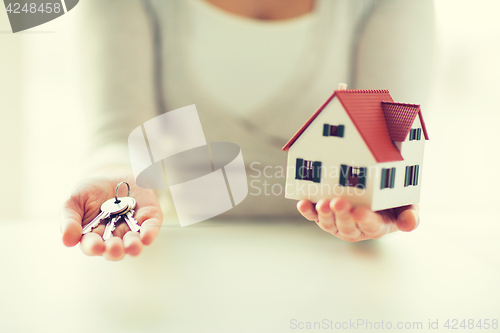 Image of close up of hands holding house model and keys