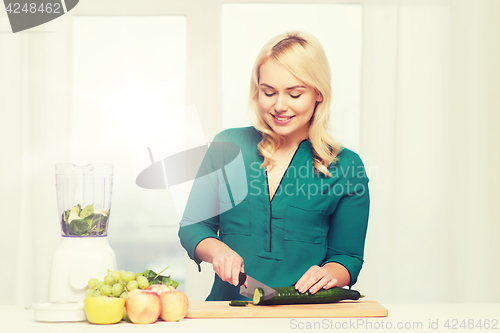 Image of smiling woman with blender cooking food at home