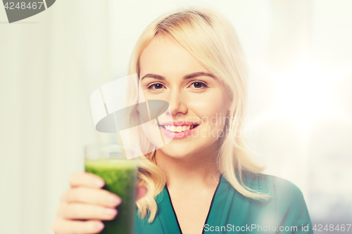 Image of smiling woman drinking juice or smoothie at home