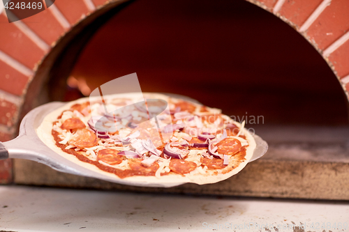 Image of peel placing pizza into oven at pizzeria