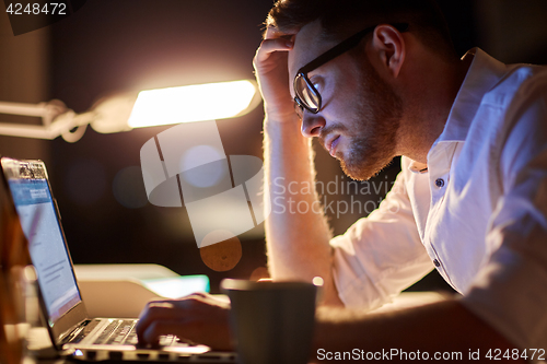 Image of businessman typing on laptop at night office