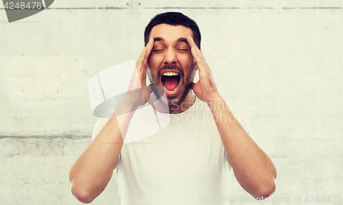 Image of crazy shouting man in t-shirt over gray wall