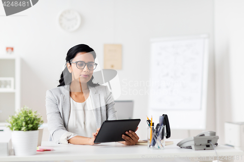 Image of smiling businesswoman with tablet pc at office