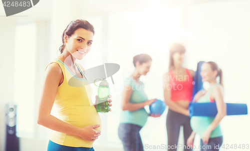 Image of happy pregnant woman with water bottle in gym