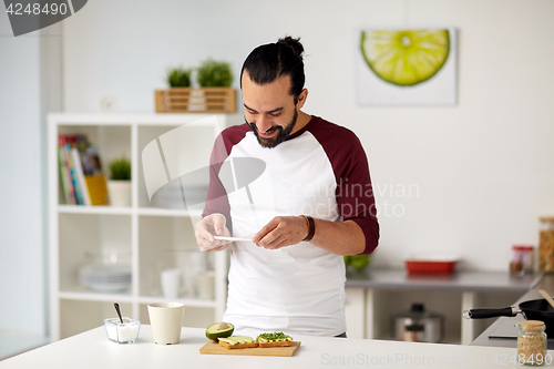 Image of man photographing food by smartphone at home