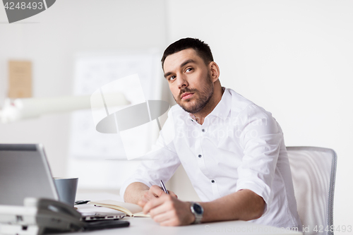 Image of businessman with laptop and notebook at office