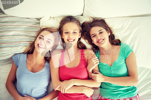 Image of happy young women in bed at home pajama party