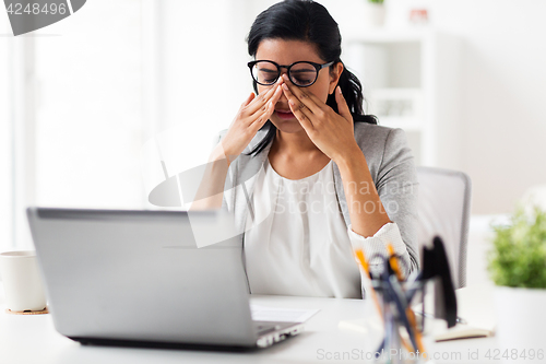 Image of businesswoman rubbing tired eyes at office