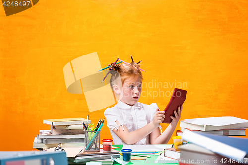 Image of The Redhead teen girl with lot of books at home. Studio shot