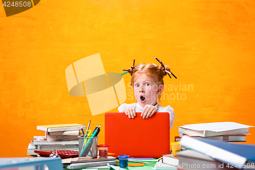Image of The Redhead teen girl with lot of books at home. Studio shot