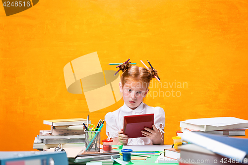Image of The Redhead teen girl with lot of books at home. Studio shot