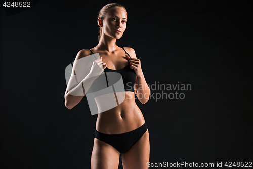 Image of Muscular young woman athlete on black