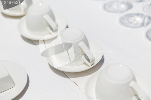 Image of white coffee cups upside down on saucers