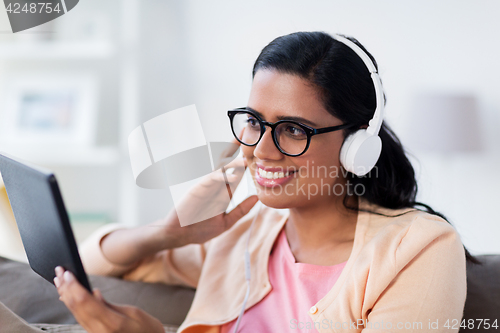 Image of happy woman with tablet pc and headphones at home