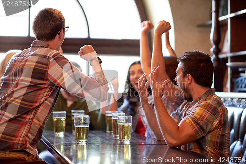 Image of football fans or friends with beer at sport bar