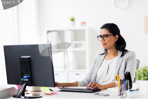 Image of happy businesswoman with computer at office