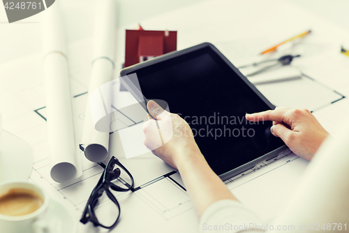 Image of close up of hand with blueprint and tablet pc