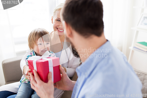 Image of happy family with birthday gift at home