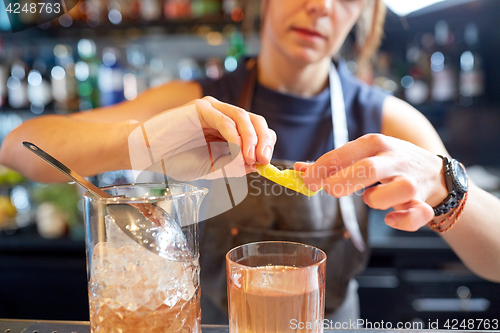 Image of bartender with glass of cocktail and lemon at bar