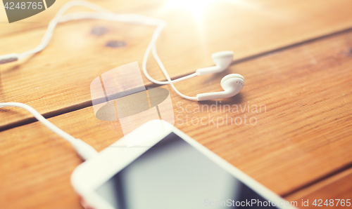 Image of close up of smartphone and earphones on wood