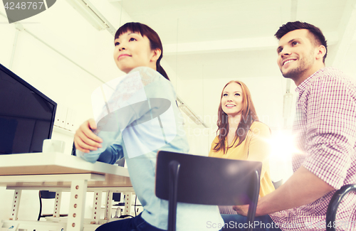 Image of happy creative team drinking coffee at office