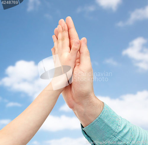 Image of father and child hands making high five over sky