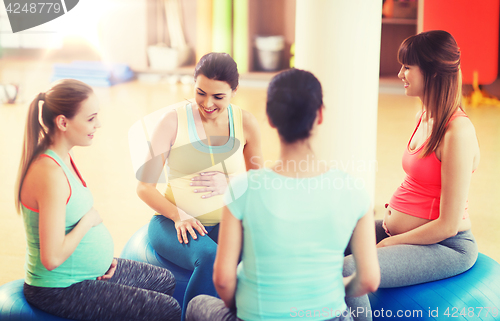 Image of happy pregnant women sitting on balls in gym