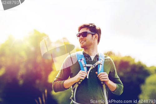 Image of happy young man with backpack hiking outdoors
