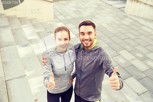 Image of smiling couple showing thumbs up on city street