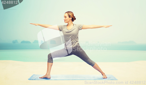 Image of woman making yoga warrior pose on mat