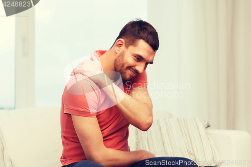 Image of unhappy man suffering from neck pain at home